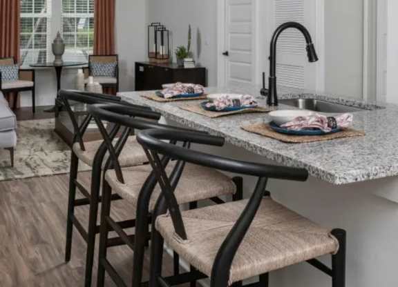 A kitchen with a table and chairs in the foreground and a window with curtains in the background. at Atwater at Nocatee Apartments, Toledo, Florida