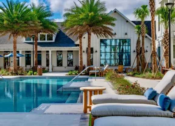 A poolside area with lounge chairs and a table. at Atwater at Nocatee Apartments, Florida, 32081