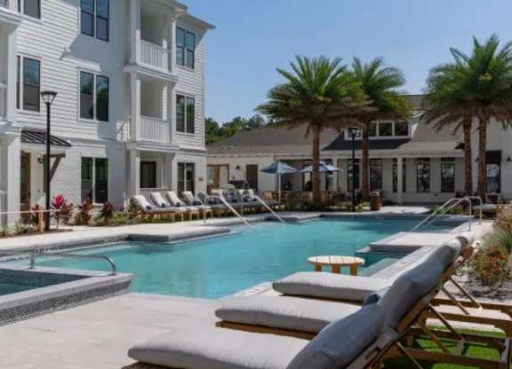 A pool with lounge chairs and a building in the background. at Atwater at Nocatee Apartments, Toledo, 32081