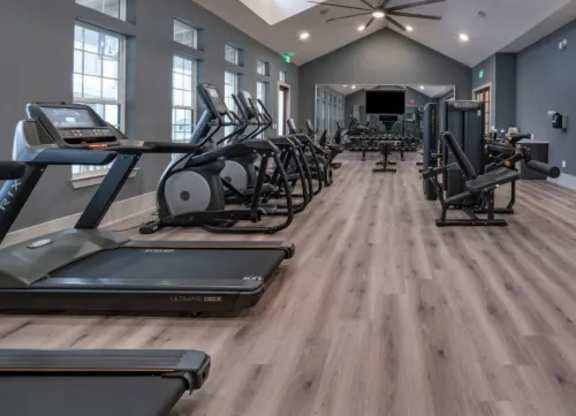 A gym with treadmills, elliptical machines, and a ceiling fan. at Atwater at Nocatee Apartments, Toledo, 32081