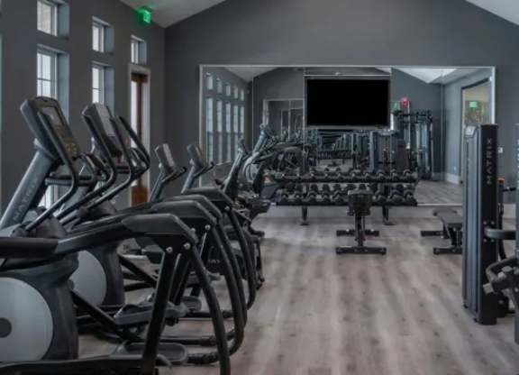 A gym with treadmills, elliptical machines, and a television. at Atwater at Nocatee Apartments, Toledo, FL