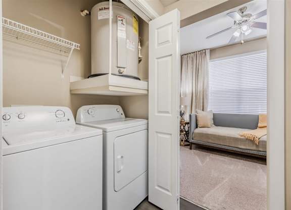 A white washing machine and dryer in a small laundry room. at The Spring at Silverton Apartments, Fort Worth, TX, 76133