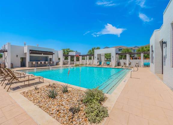 A swimming pool surrounded by a tiled patio and a small garden. at The Spring at Silverton Apartments, Fort Worth, Texas