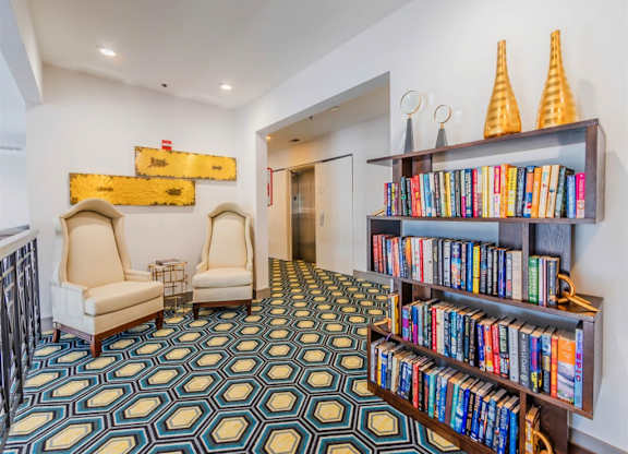 A room with a patterned carpet and a bookshelf filled with books. at The Spring at Silverton Apartments, Texas, 76133