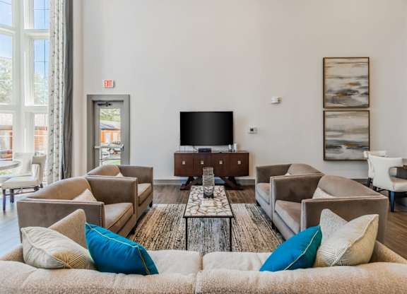A living room with a large couch and a flat screen TV. at The Spring at Silverton Apartments, Texas