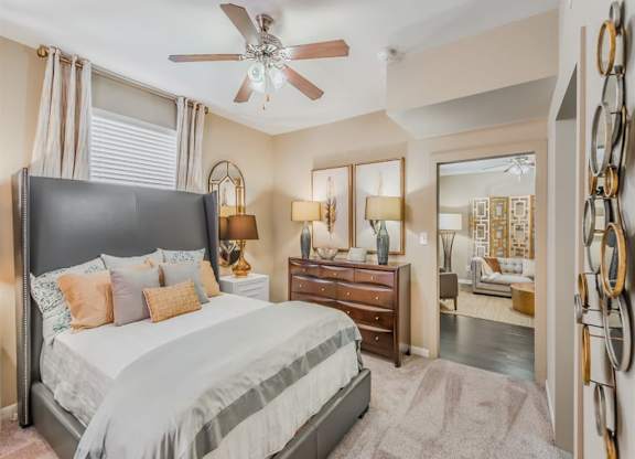 A bedroom with a large bed, a dresser, and a ceiling fan. at The Spring at Silverton Apartments, Texas, 76133