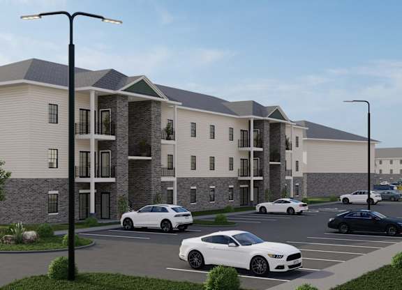 A modern apartment complex with cars parked in the driveway.