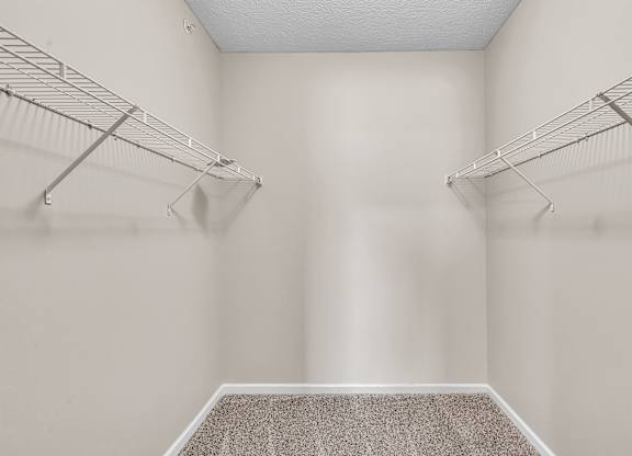 A walk-in closet with a carpeted floor and metal racks.