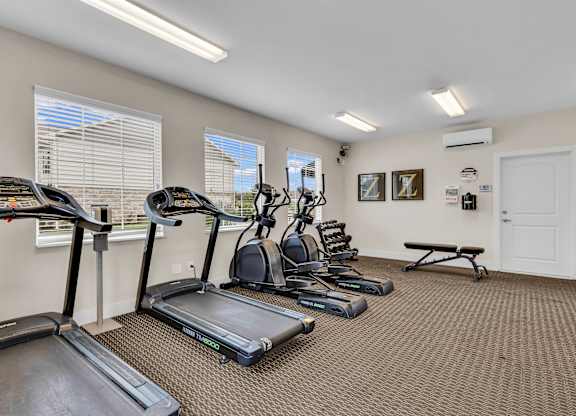 A room with a treadmill, elliptical trainer, and other exercise equipment.