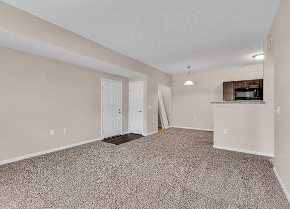 A room with a carpeted floor and a flat screen TV mounted on the wall.