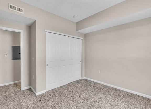 A room with a white door and a carpeted floor.