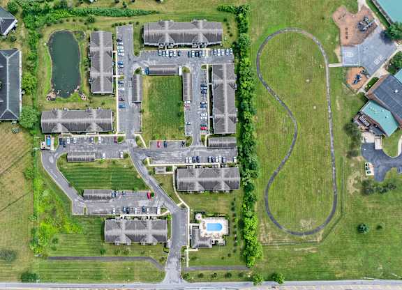 A bird's eye view of a residential area with houses, roads, and a small pond.