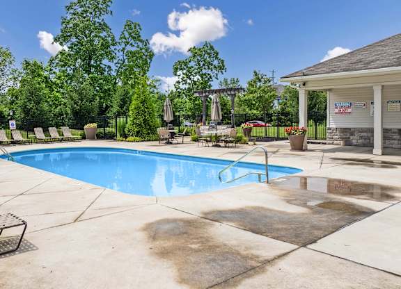 A pool surrounded by trees and a building in the background.