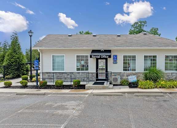 A rental office building with a parking lot in front.
