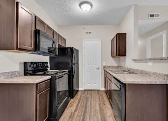 A kitchen with brown cabinets and black appliances.