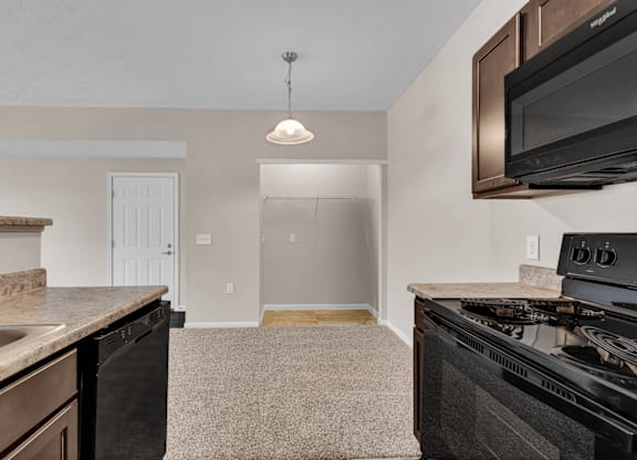 A kitchen with a black stove top oven and a black microwave above it.