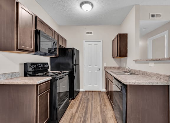 A kitchen with brown cabinets and a black refrigerator.