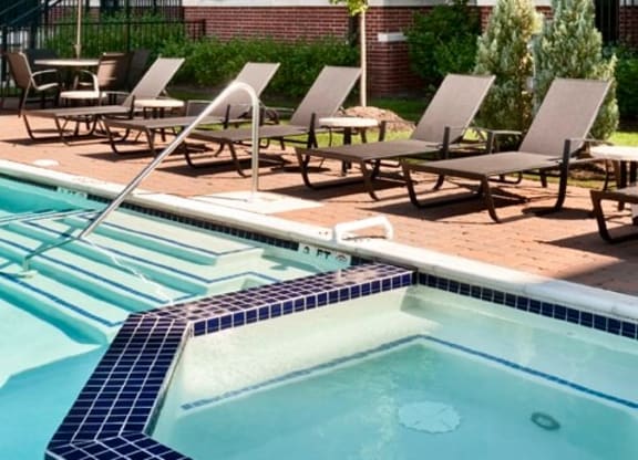 a swimming pool with chaise lounge chairs in front of a brick building  at The Sheffield Englewood, Englewood