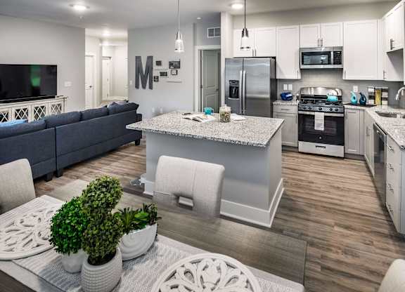 A modern kitchen with a blue sofa and white cabinets.