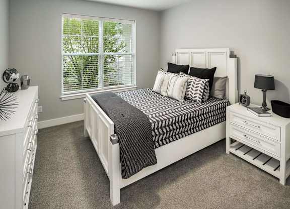 A bedroom with a large bed and a window with blinds.