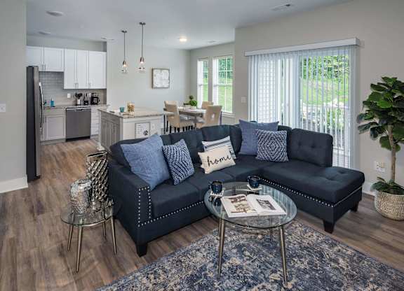 A modern living room with a black sofa and a glass coffee table.