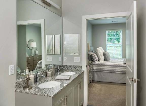 A bathroom with a toilet, sink, mirror and a patterned rug.