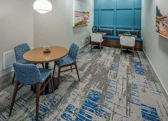 A room with a round table and chairs with a carpet on the floor.