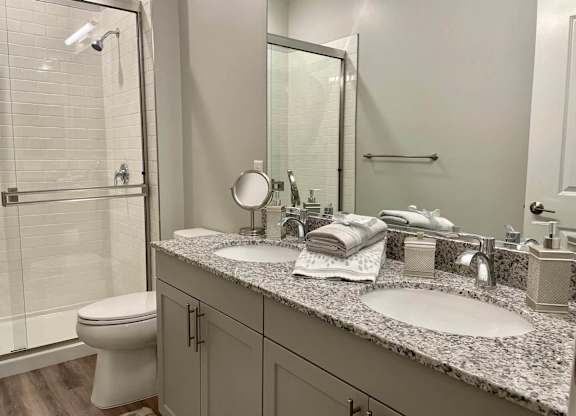 A bathroom with a toilet, sink, mirror, and shower.