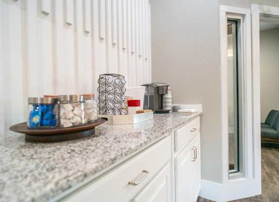 A kitchen counter with a jar of blue candies and a silver container.