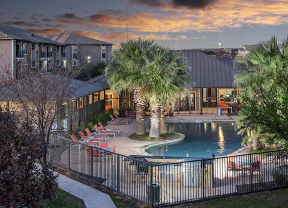 A pool surrounded by palm trees and chairs.
