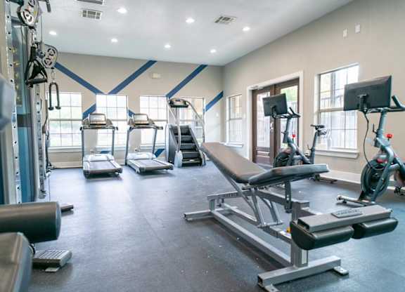 A gym with a variety of equipment including treadmills, weights, and exercise machines.