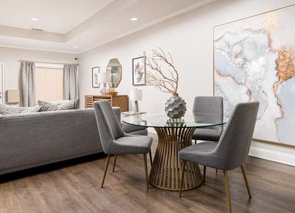 A modern dining room with a glass table and grey chairs.