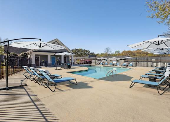 A pool area with sun loungers and a building in the background.