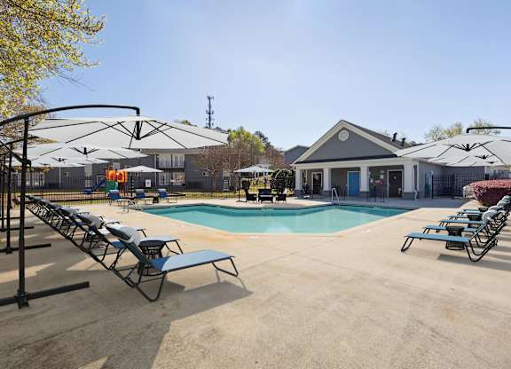 A pool area with sun loungers and a building in the background.