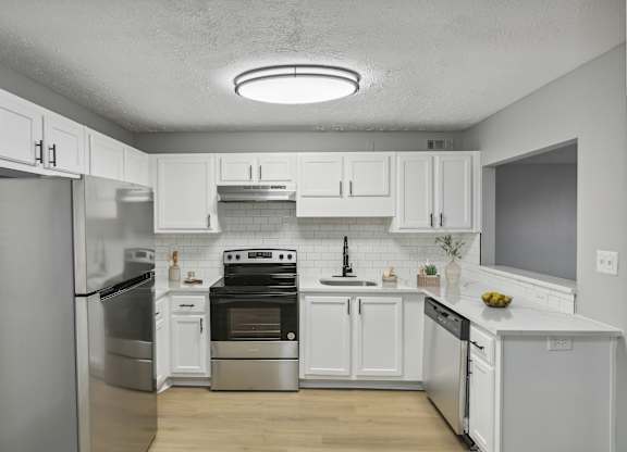 A modern kitchen with white cabinets and stainless steel appliances.