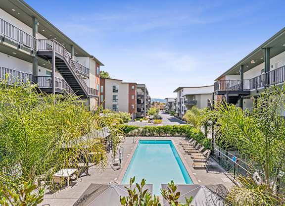 A pool surrounded by buildings and trees.
