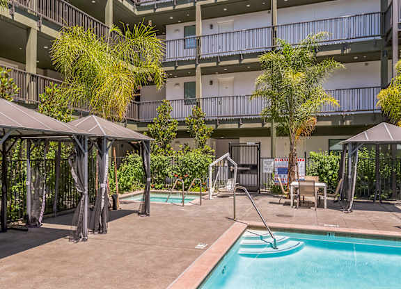 A pool area with a hot tub and umbrellas.
