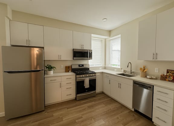 A kitchen with white cabinets and a stainless steel refrigerator.