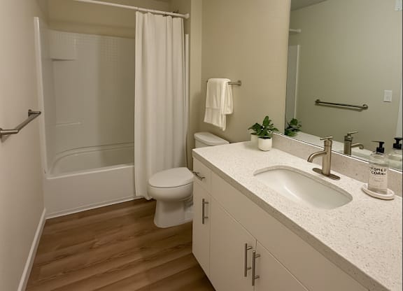 A white bathroom with a toilet, sink, and shower.