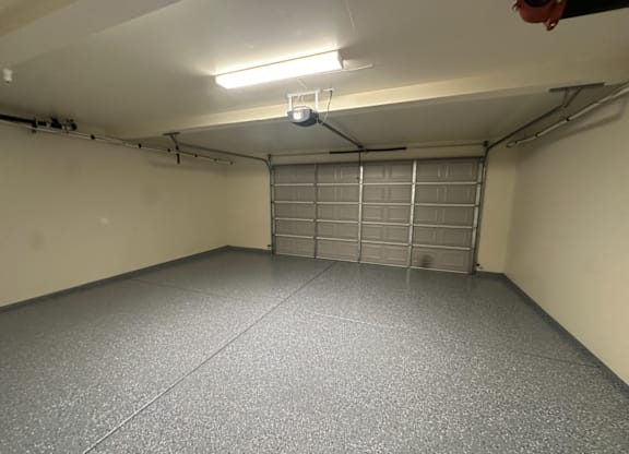 A garage with a closed metal door and a light on the ceiling.