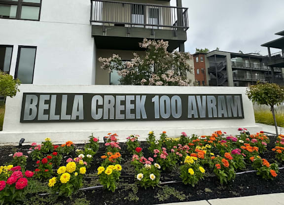 A white building with a sign that says Bella Creek 100 Avram.