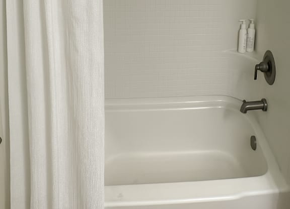 A white bathroom with a white tub and shower curtain.