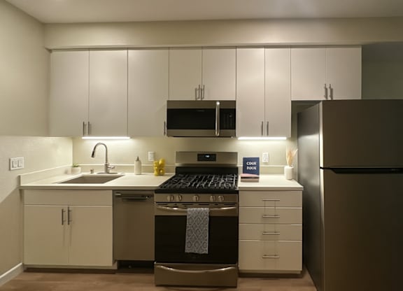 A modern kitchen with white cabinets and stainless steel appliances.