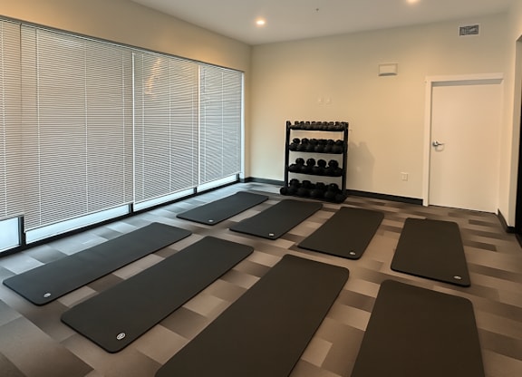 A room with yoga mats on the floor and a rack of dumbbells.