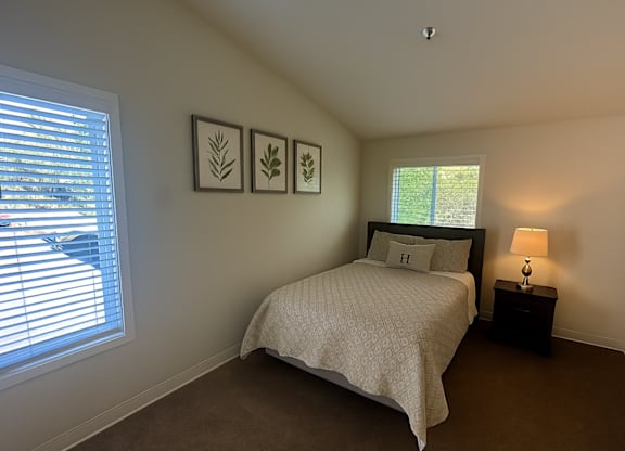 A bedroom with a bed, nightstand, and two wall art pieces.