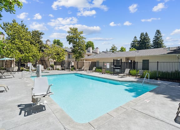 A large swimming pool surrounded by lounge chairs and trees.