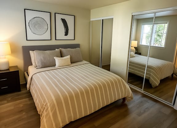 A bedroom with a large bed and a mirrored closet door.