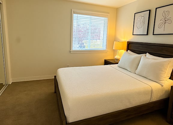 A bedroom with a large bed and two framed pictures on the wall.