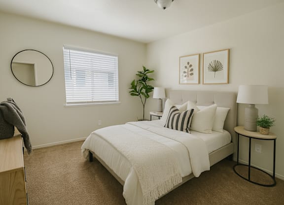 A bedroom with a bed, nightstand, and a plant.