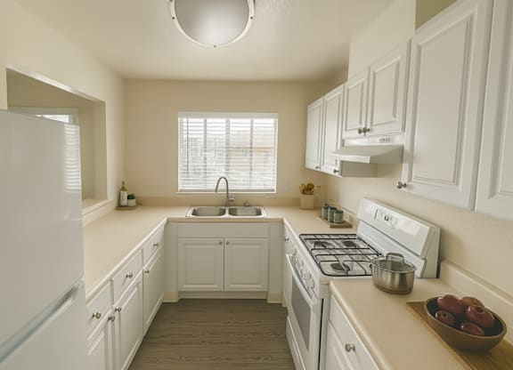 A white kitchen with a sink and a window.